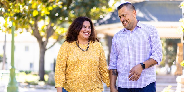 Plus-size woman walks hand-in-hand with her taller male partner.