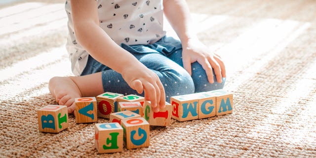 child plays with wooden cubes with colorful letters