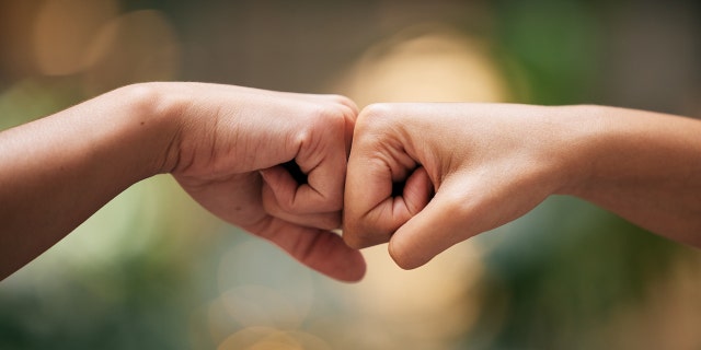 Close-up of fist-bumping hands.