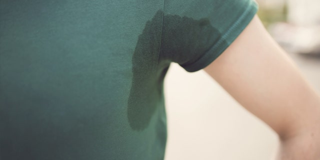 Close up of a person's sweaty underarm with pit stains on shirt.