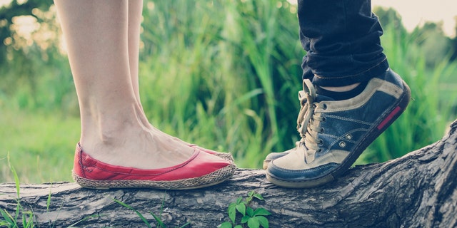 Close-up view of shoes in which it appears a boy is getting on his tip toes to kiss a girl.