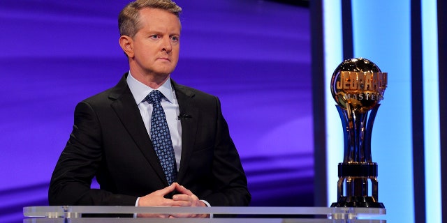 Ken Jennings looks serious with his hands together behind the podium during "Jeopardy"