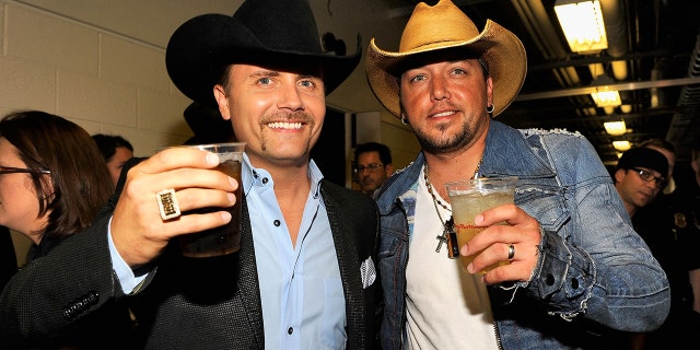 Jason Aldean and John Rich wear cowboy hats and toast backstage