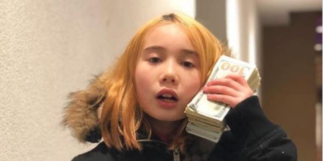 Lil Tay holds $100 bills and wears Louis Vuitton purse