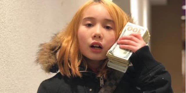 Lil Tay holds $100 bills and wears Louis Vuitton purse