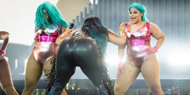 Lizzo on stage in the UK with her dancers with her butt facing the crowd