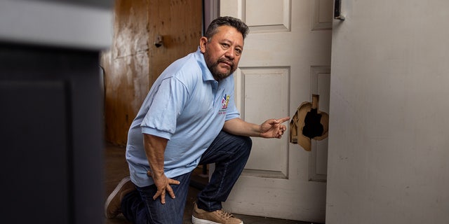 North Hollywood print shop owner Carlos Pena points to damaged door