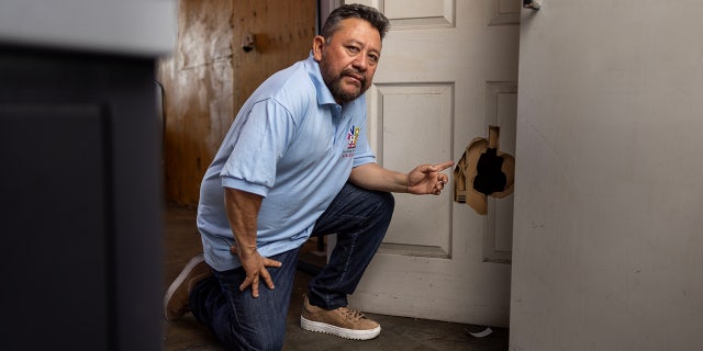 North Hollywood print shop owner Carlos Pena points to damaged door