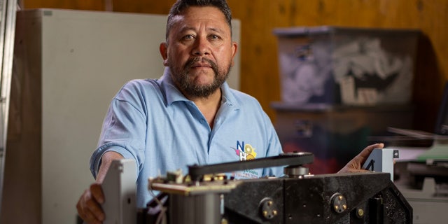 Shop owner stands behind large printing machine