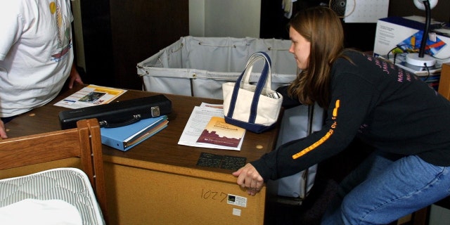 A student moving furniture around her college dorm