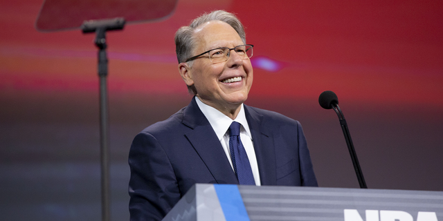 NRA CEO Wayne LaPierre behind lectern smiling