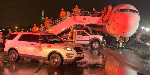 Firefighters guide passengers of an Alaska Airlines plane