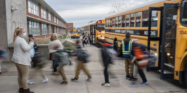 teacher waves to her students near buses