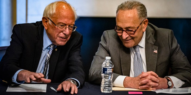 Senators Bernie Sanders and Chuck Schumer sit together at a table