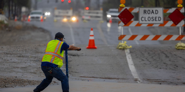 Worker tries to control flooded roadway