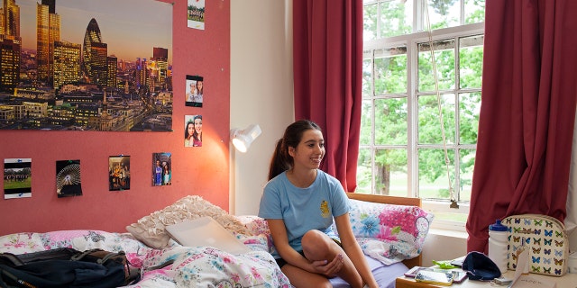 A college student sitting in her decorated dorm room