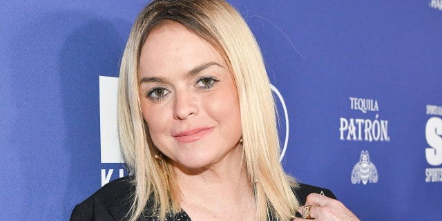 Taryn Manning with bright blonde hair in a black shirt tilts her head slightly to the right on the carpet
