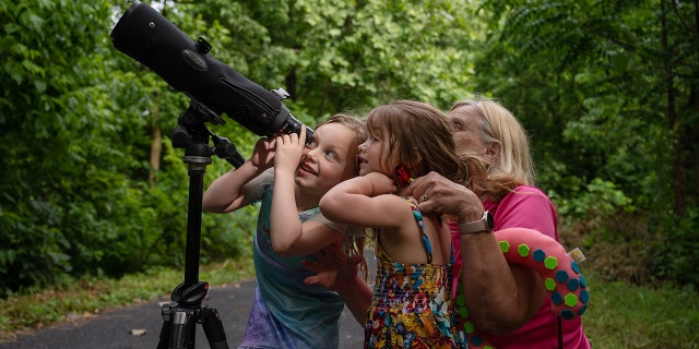 Three people using a telescope