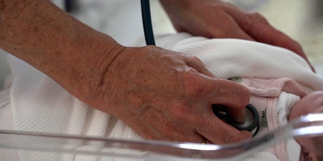 Nurse uses stethoscope on baby