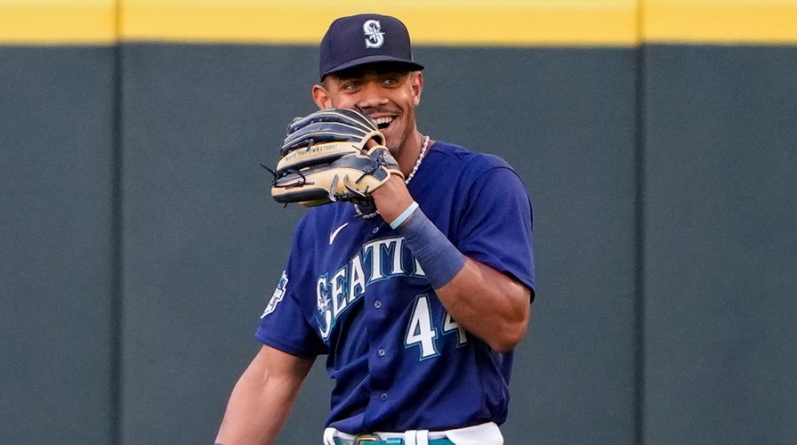 Seattle Mariners' Julio Rodriguez smiles as he speaks with a coach