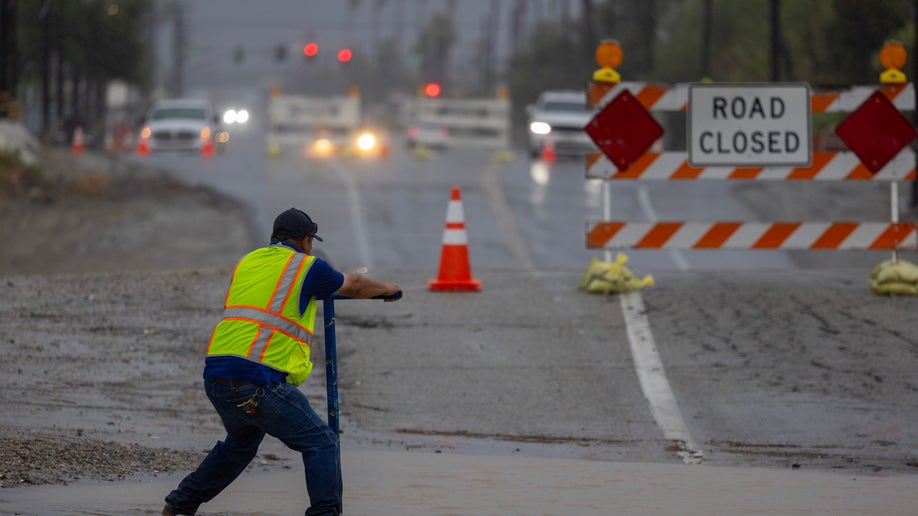 Worker tries to control flooded roadway