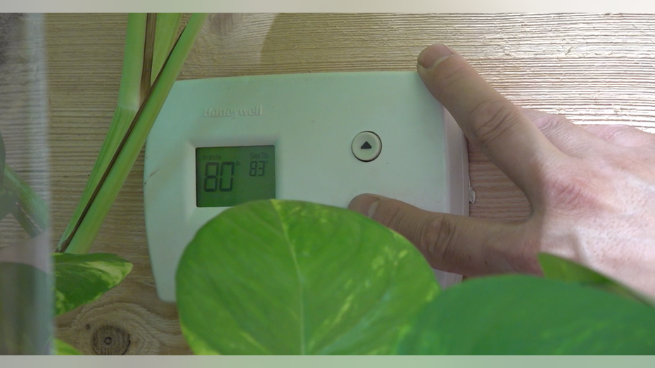 A hand changing the temperature on the thermostat.