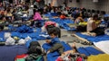 Recently arrived migrants sit on cots and the floor of a makeshift shelter operated by the city at O'Hare International Airport on Aug. 31, 2023. (Armando L. Sanchez/Chicago Tribune/Tribune News Service via Getty Images)