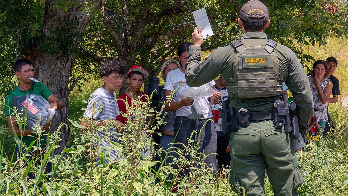 migrants who have crossed into the U.S. from Mexico in Eagle Pass, Texas, listen to instructions from a Border Patrol Agent