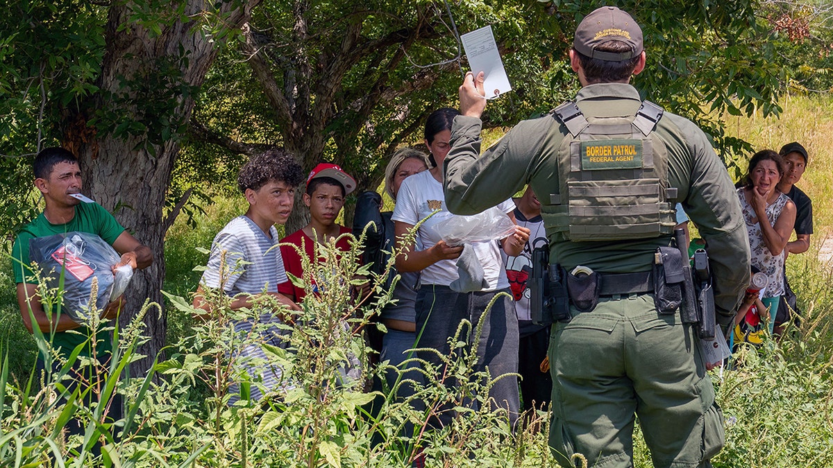 migrants who have crossed into the U.S. from Mexico in Eagle Pass, Texas, listen to instructions from a Border Patrol Agent