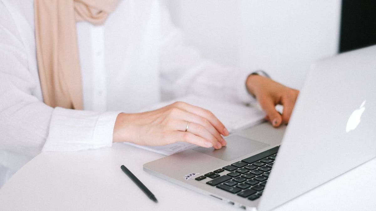 Woman typing on her Apple laptop.