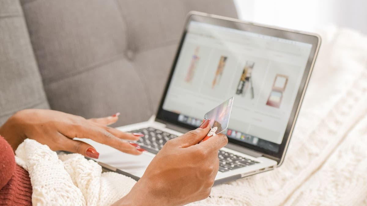A woman shopping on a laptop while holding a credit card.