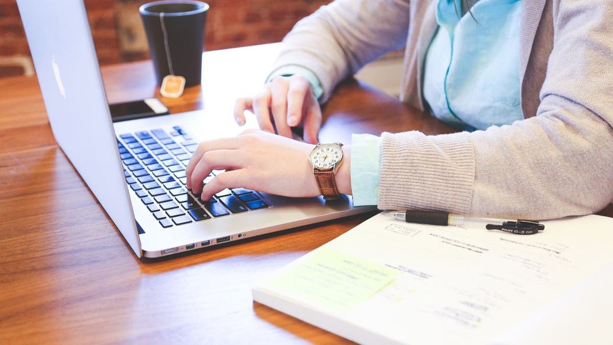 Woman sitting at the table and typing on her laptop.