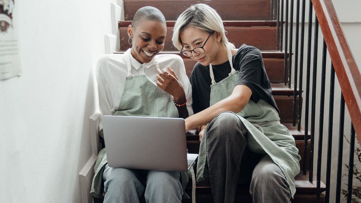 Two women in aprons looking at a laptop