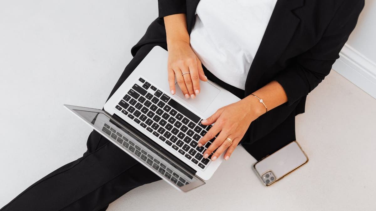 Photo of a woman sitting down with a laptop on her lap.