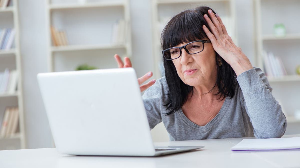 Woman visibly upset, looking at her copmuter.