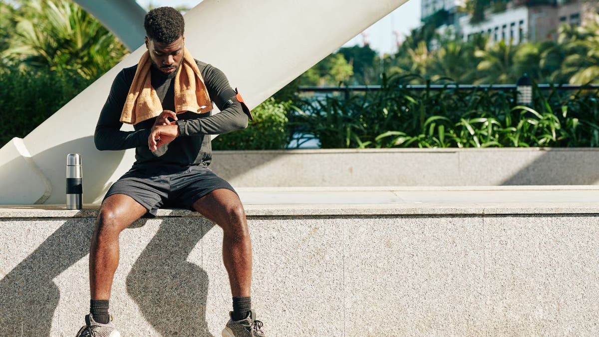 Stock photo shows a man checking his fitness tracker on his wrist