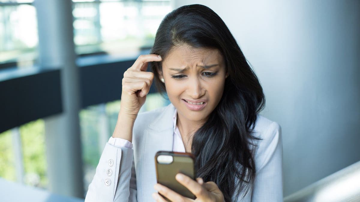 Woman staring at her phone with a confused look.