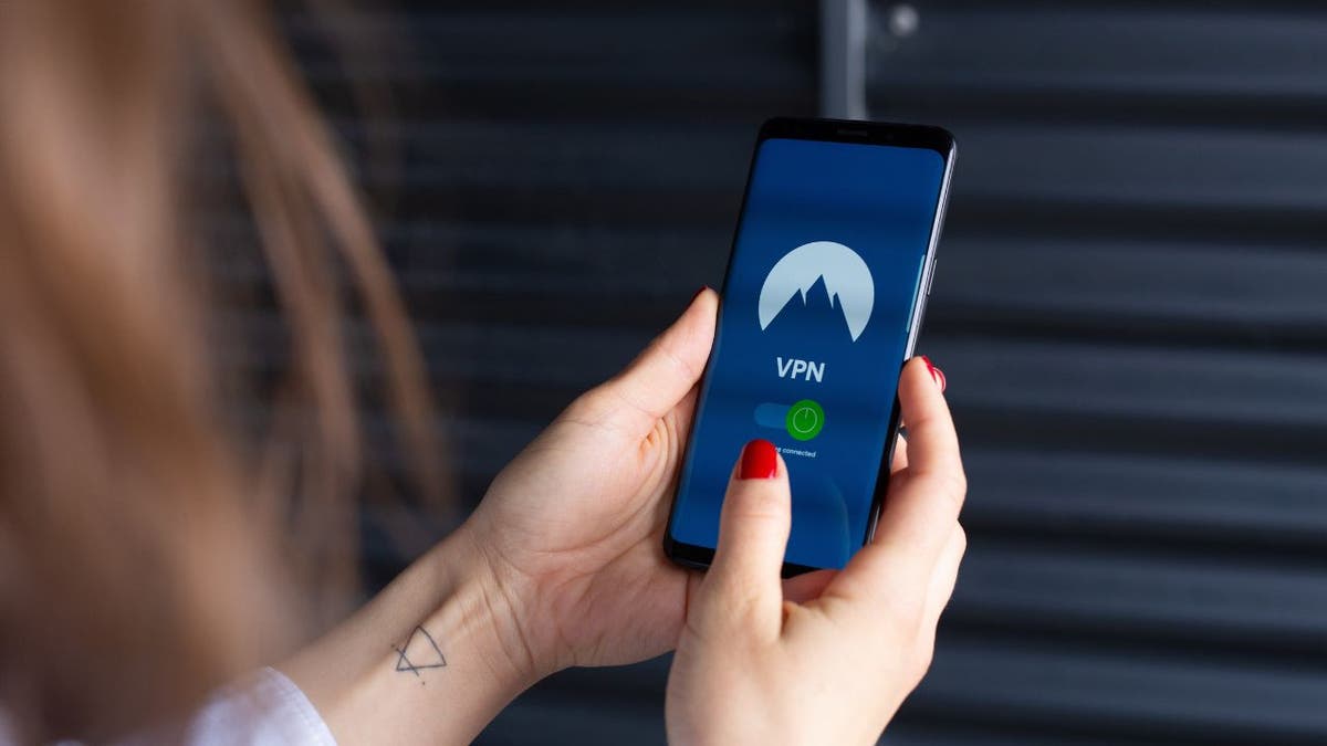 Woman holding up her phone while logging into her VPN.
