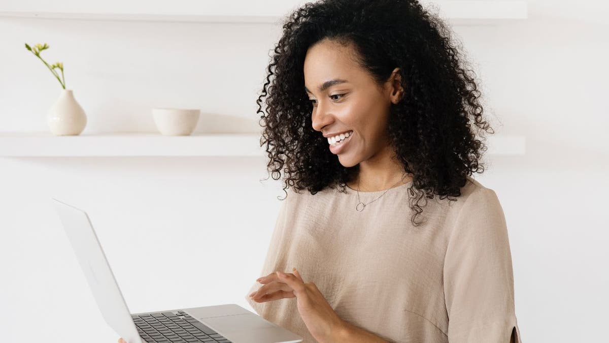 Woman smiling while looking at her laptop