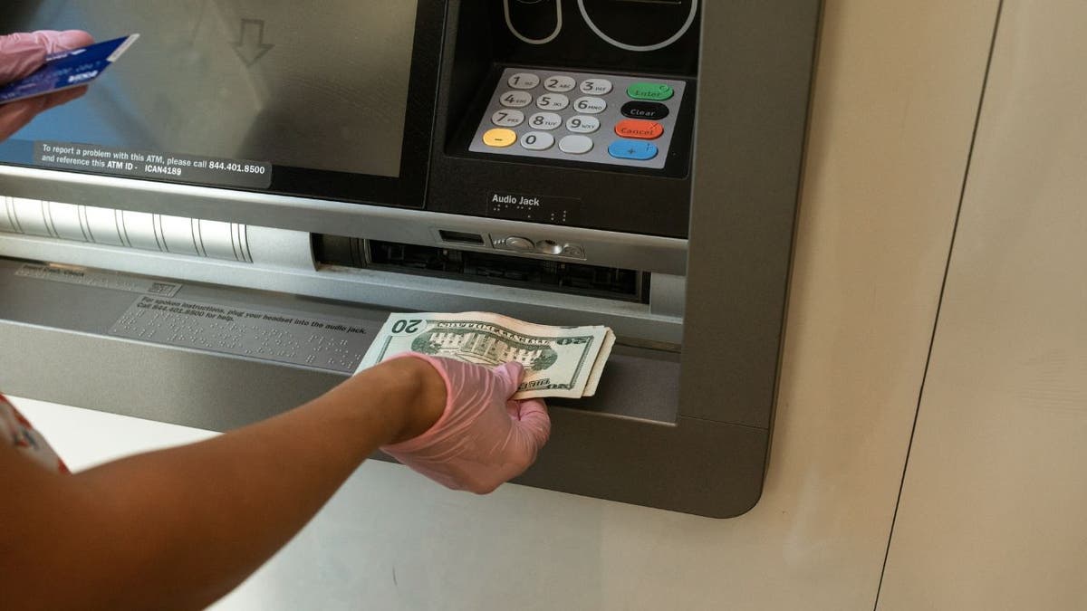 امرأة تأخذ النقود من ماكينة الصراف الآلي.