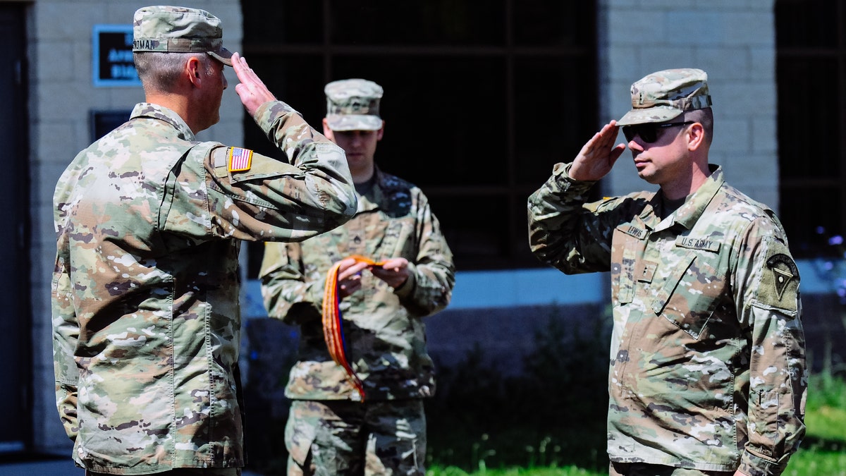 Army members salute during ceremony