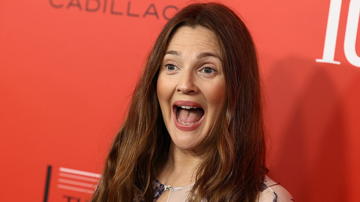 Drew Barrymore with her mouth ajar smiling on the carpet 