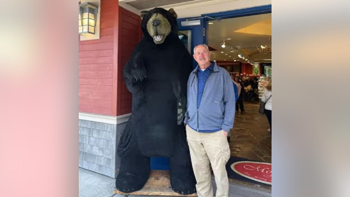 Andy Probst standing next to a giant-sized stuffed black bear outside a doorway