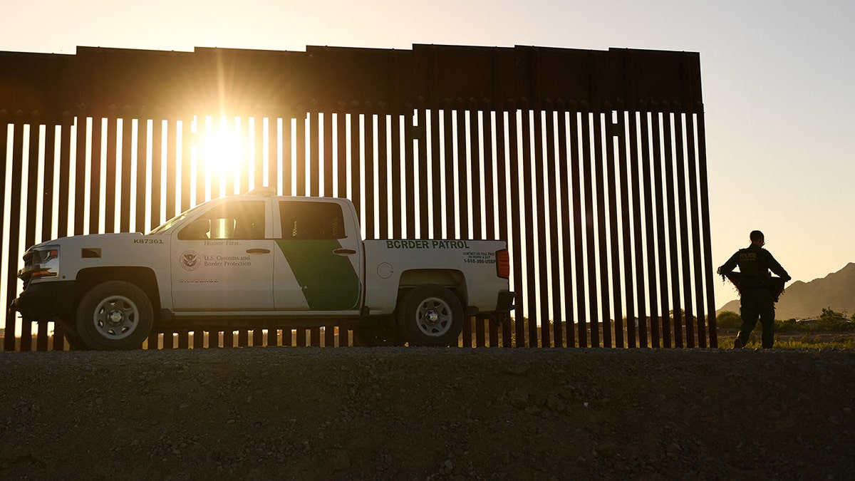 A Border Patrol agent walks between a gap along the border wall between the US and Mexico in Yuma, Arizona on June 1, 2022. 