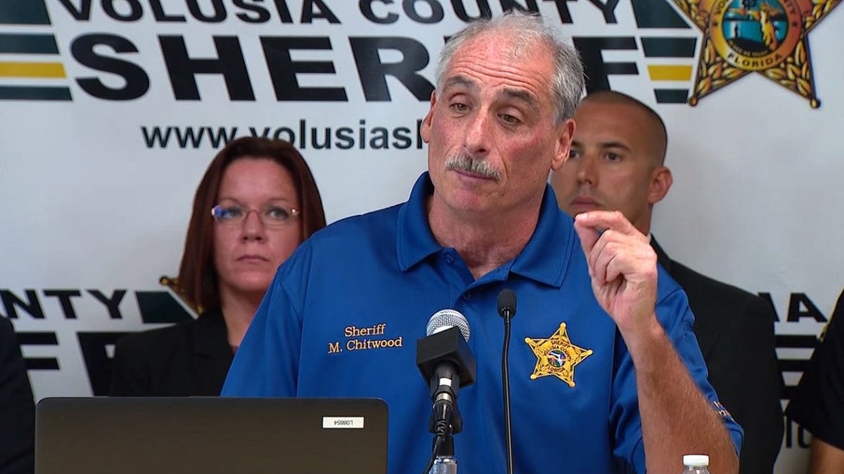 Volusia County Sheriff Michael Chitwood, wearing a blue sheriff's office polo shirt, speaks to reporters during a news conference