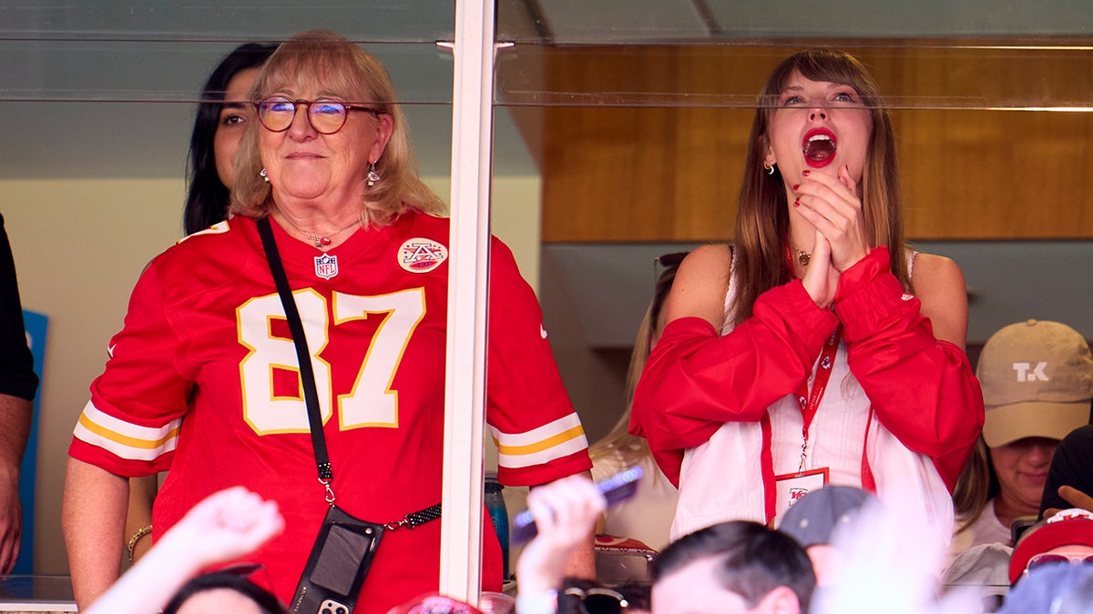 Taylor Swift claps at a football game