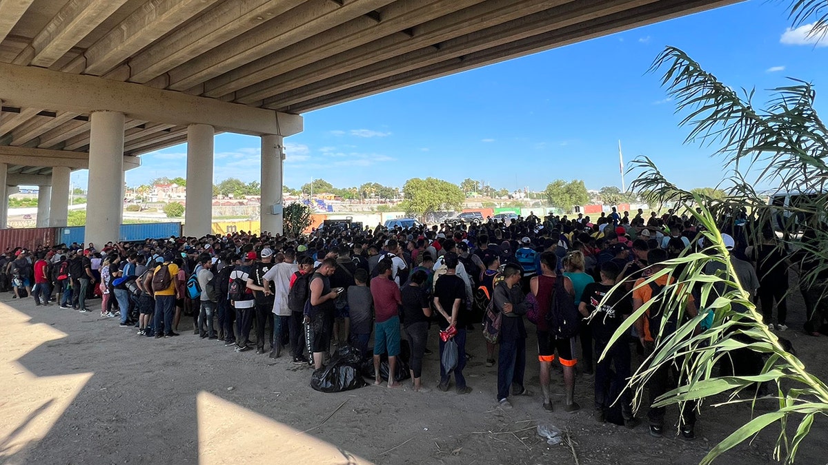 Migrants gather under bridge