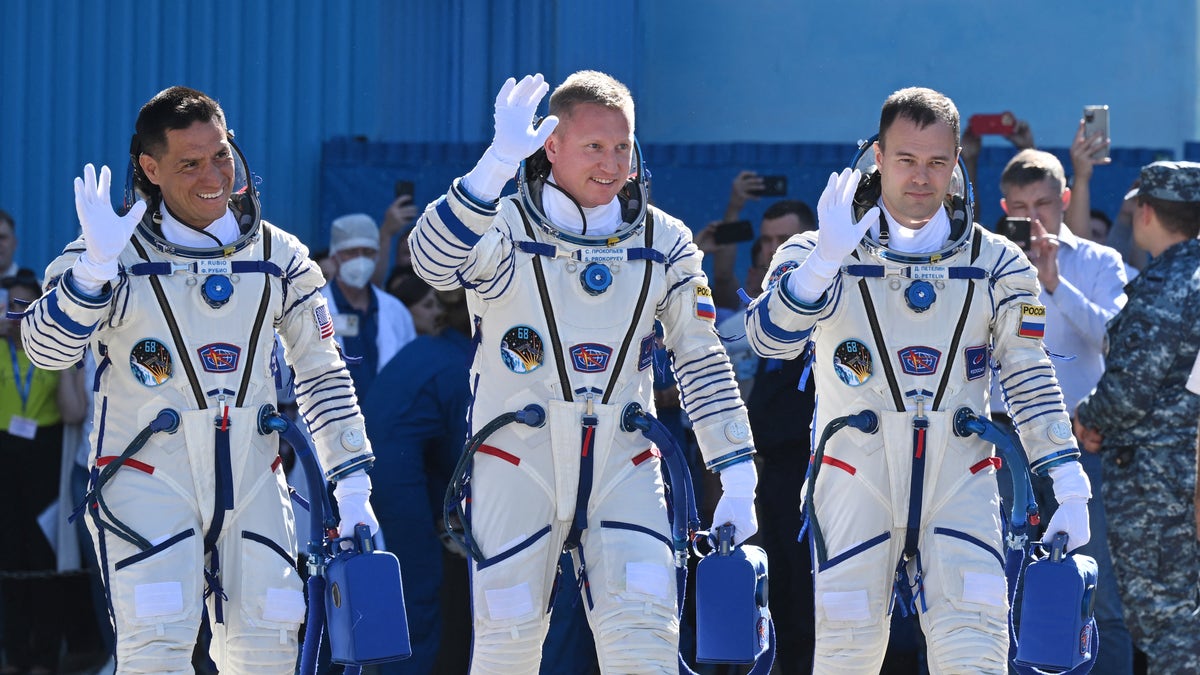 Frank Rubio and his Russian cosmonaut team members in space suits waving to the press.