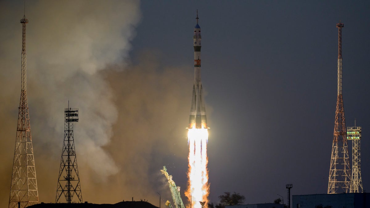 A Russian Soyuz rocket moments after launching with fire emerging from the tail lighting up a dark sky.