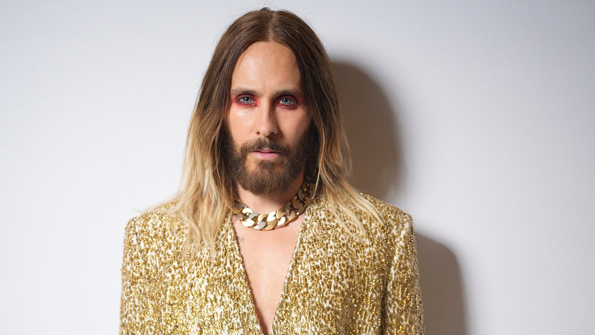 Jared Leto in a gold jacket with pink eye makeup